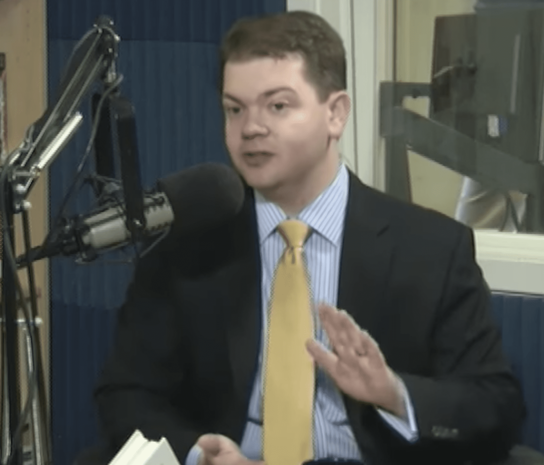 A man in suit and tie talking on the radio.