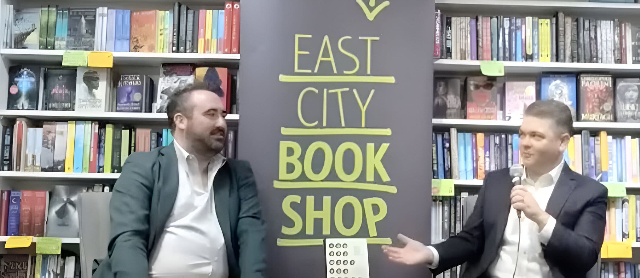 A man and woman in front of a book shop sign.